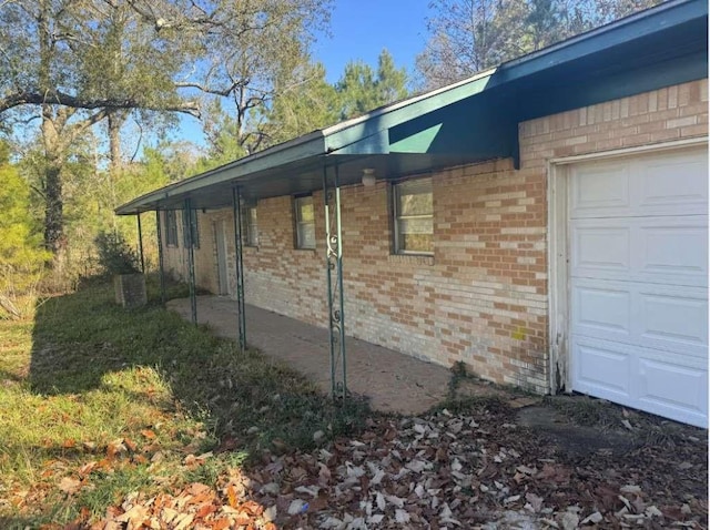 view of side of home featuring an attached garage and brick siding