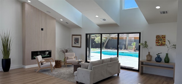 living room featuring visible vents, a large fireplace, high vaulted ceiling, and wood finished floors