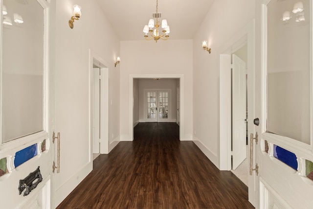 hallway with dark wood-style floors, baseboards, visible vents, an inviting chandelier, and french doors