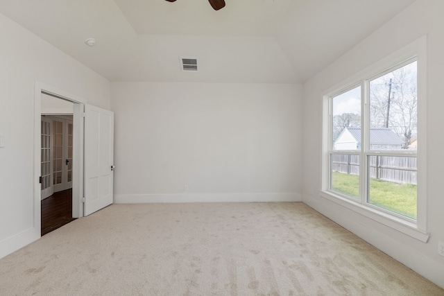 carpeted empty room featuring vaulted ceiling, baseboards, visible vents, and ceiling fan