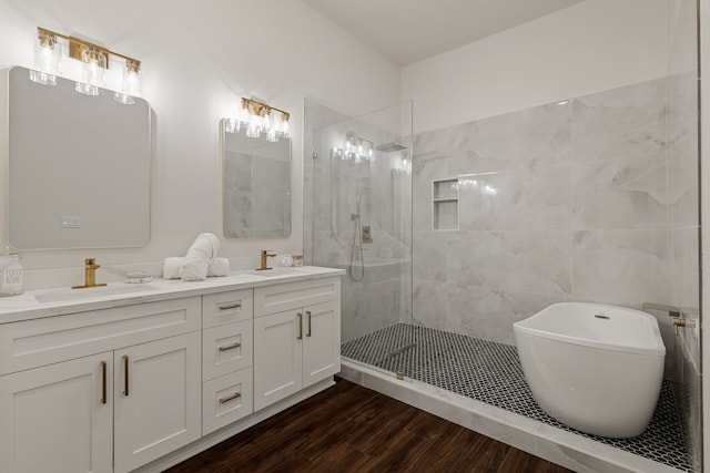 full bath featuring walk in shower, a freestanding bath, double vanity, wood finished floors, and a sink