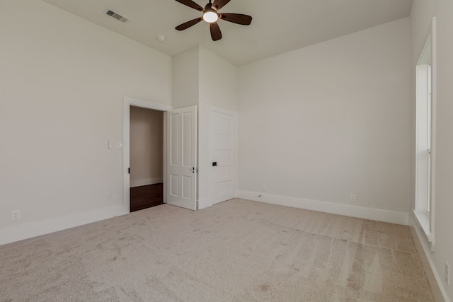 spare room with a ceiling fan, carpet, visible vents, baseboards, and a towering ceiling