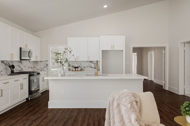 kitchen with a center island with sink, appliances with stainless steel finishes, white cabinetry, and a sink