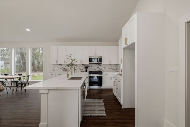 kitchen featuring dark wood-style floors, a sink, range with gas cooktop, stainless steel microwave, and tasteful backsplash