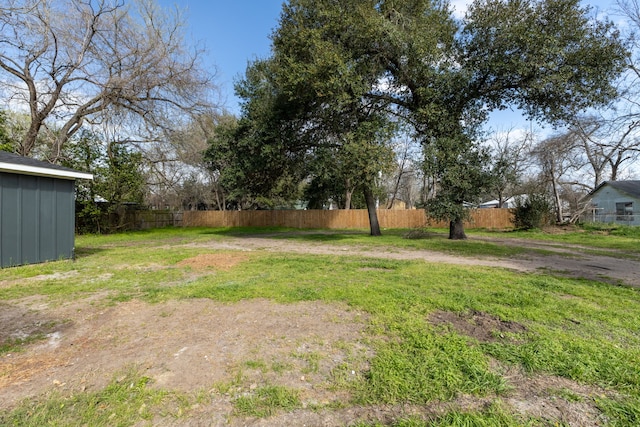 view of yard with dirt driveway and fence