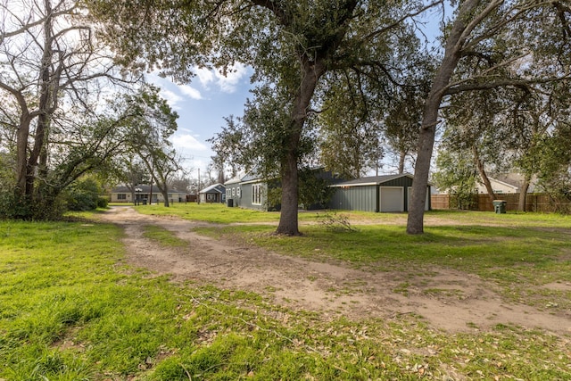 view of yard with an outbuilding, fence, a garage, and driveway