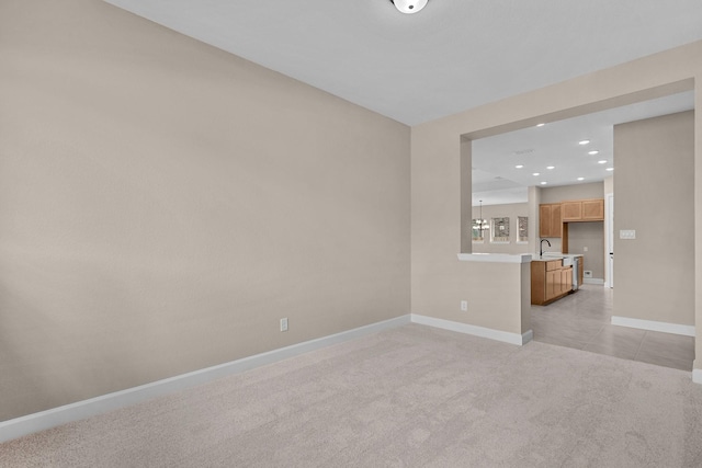 spare room featuring baseboards, light carpet, light tile patterned floors, recessed lighting, and a sink