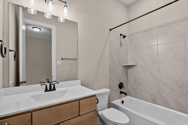 bathroom featuring shower / bathing tub combination, toilet, vanity, and a textured wall