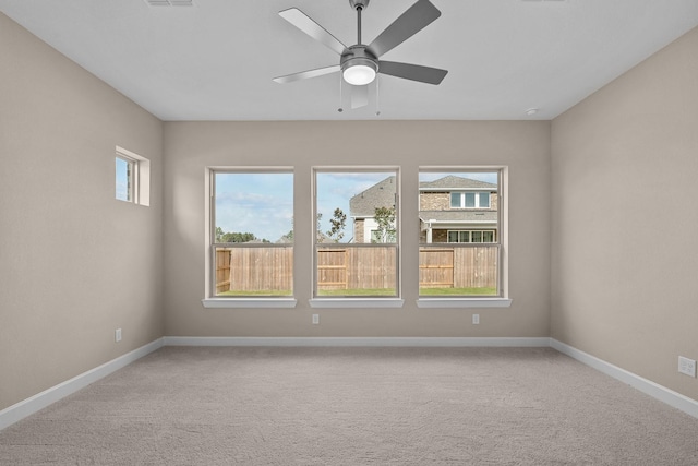 empty room featuring a ceiling fan, light colored carpet, and baseboards