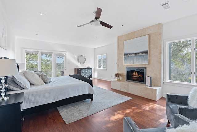 bedroom featuring visible vents, wood finished floors, a fireplace, baseboards, and ceiling fan