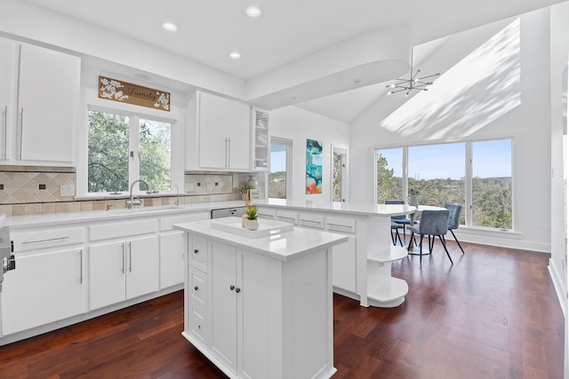 kitchen featuring a sink, open shelves, backsplash, a peninsula, and light countertops