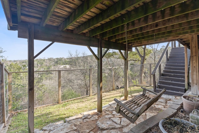 view of patio / terrace featuring stairway, fence, and a wooded view