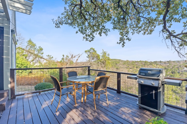 wooden terrace with outdoor dining area and a grill