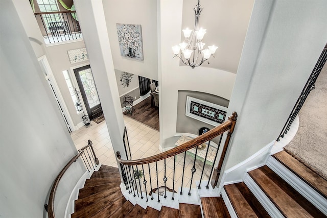 staircase featuring a high ceiling, plenty of natural light, wood finished floors, and a chandelier