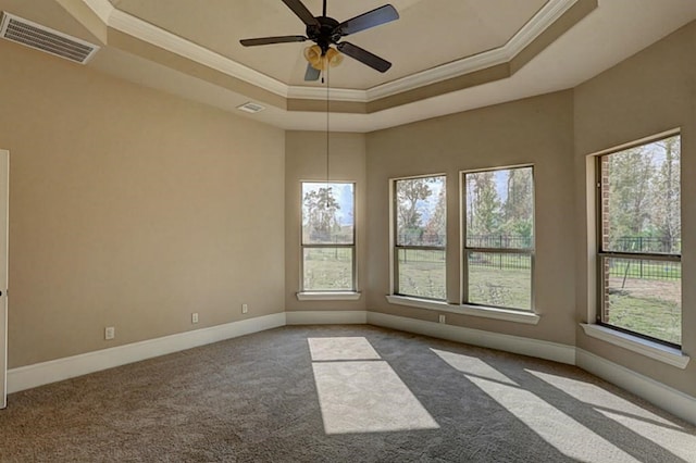 carpeted spare room with a tray ceiling, baseboards, visible vents, and ornamental molding