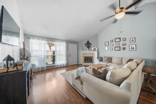 living room featuring a ceiling fan, dark wood-style flooring, a fireplace, and vaulted ceiling