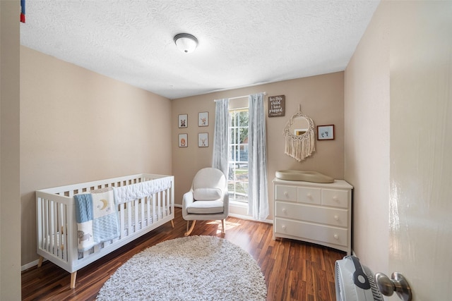 bedroom with a textured ceiling, baseboards, and wood finished floors