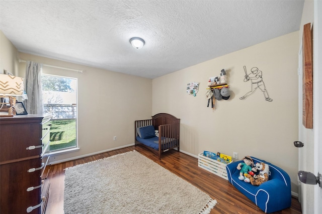 bedroom featuring a textured ceiling, baseboards, and wood finished floors