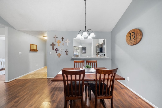 dining room featuring baseboards, an inviting chandelier, wood finished floors, and vaulted ceiling