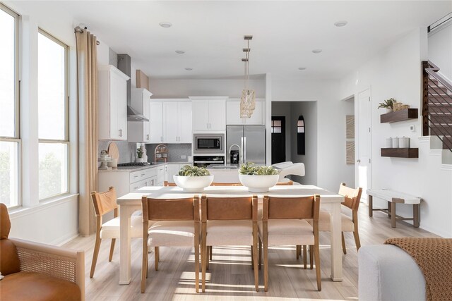 26711 Grandiflora Dr, Magnolia, TX 77355 - kitchen with appliances with stainless steel finishes, wall chimney exhaust hood, light wood-style floors, light countertops, and backsplash