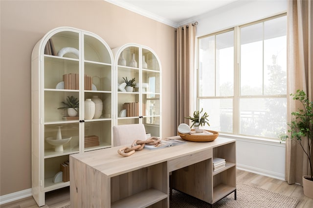 dining room featuring a wealth of natural light, light wood-type flooring, baseboards, and ornamental molding