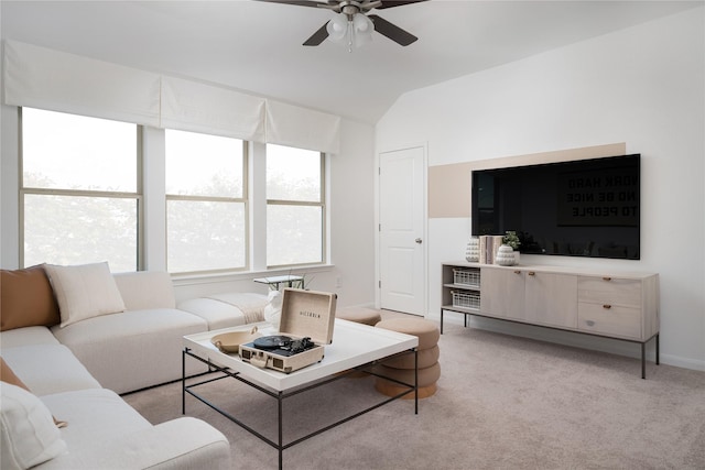 living area with ceiling fan, vaulted ceiling, baseboards, and light carpet