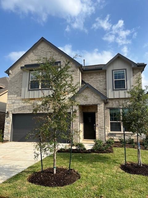 26711 Grandiflora Dr, Magnolia, TX 77355 - view of front of home featuring brick siding, a front yard, concrete driveway, a garage, and board and batten siding