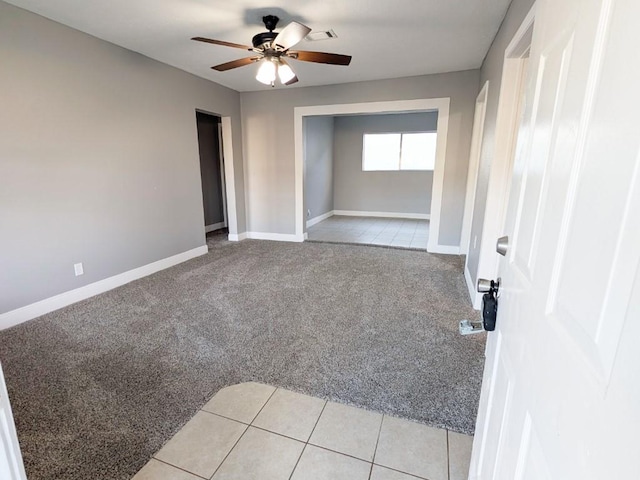 unfurnished room with light carpet, baseboards, ceiling fan, and light tile patterned flooring