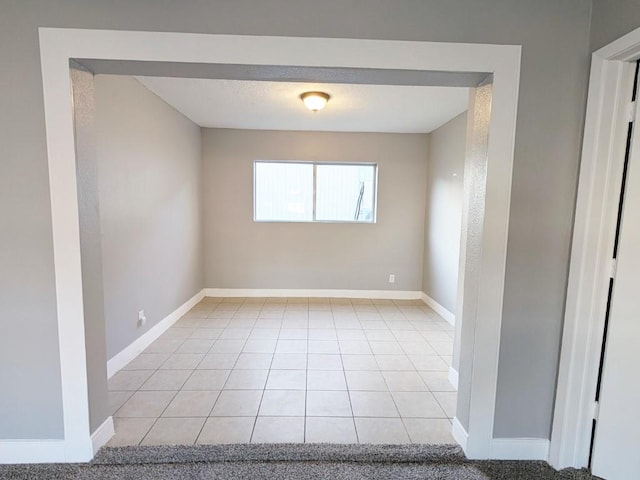 unfurnished room featuring light tile patterned flooring, baseboards, and a textured ceiling