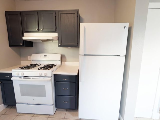 kitchen with under cabinet range hood, white appliances, light countertops, and light tile patterned flooring