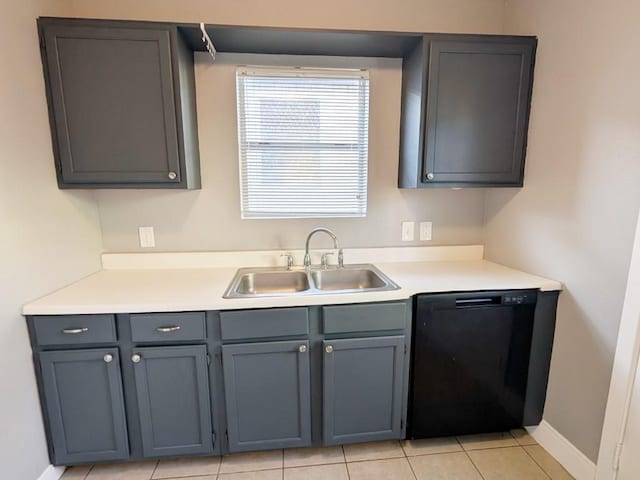 kitchen featuring baseboards, dishwasher, light countertops, gray cabinets, and a sink