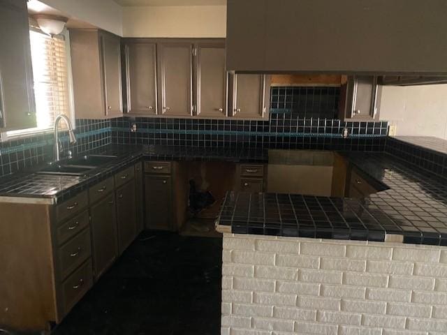 kitchen with decorative backsplash, tile counters, and a sink