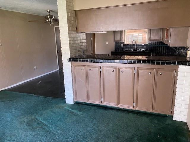 kitchen with a sink, tasteful backsplash, dark carpet, tile countertops, and ceiling fan