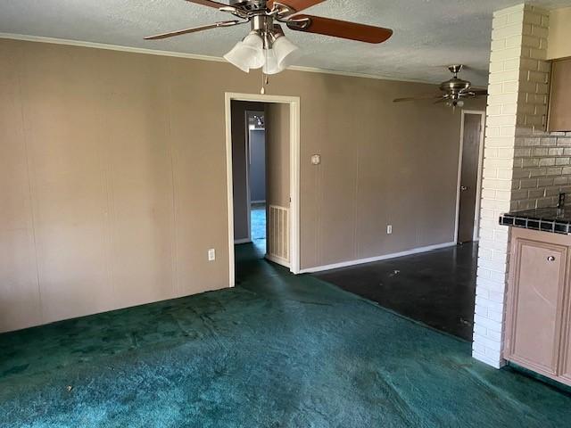 unfurnished living room featuring visible vents, ornamental molding, a ceiling fan, a textured ceiling, and dark carpet