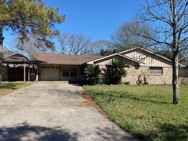 ranch-style house featuring a front yard, an attached garage, brick siding, and driveway