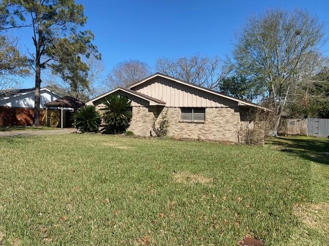 view of side of property with a yard, fence, and brick siding