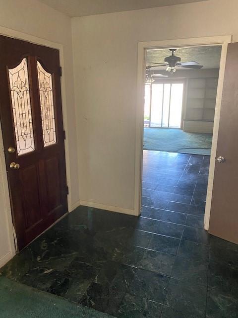 foyer with baseboards and a ceiling fan