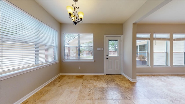 doorway featuring baseboards, plenty of natural light, and an inviting chandelier