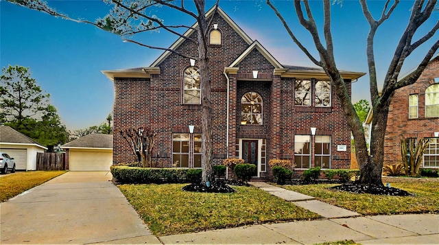 view of front facade featuring a detached garage, brick siding, and a front yard