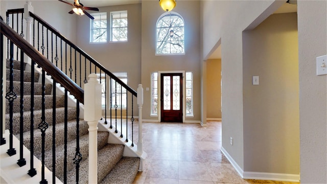 entryway featuring light tile patterned floors, baseboards, and a towering ceiling