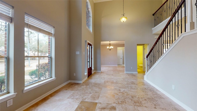 foyer entrance featuring a wealth of natural light, baseboards, a high ceiling, and an inviting chandelier