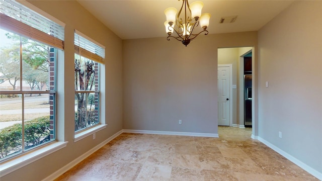 unfurnished room with visible vents, a healthy amount of sunlight, an inviting chandelier, and baseboards