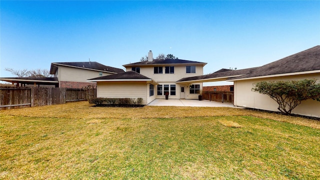 back of house featuring a patio area, a lawn, a fenced backyard, and a chimney