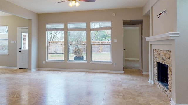 unfurnished living room featuring a fireplace, baseboards, and ceiling fan