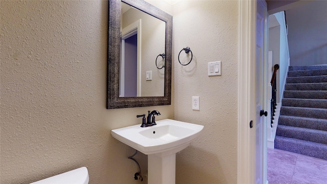 half bathroom with toilet and a textured wall