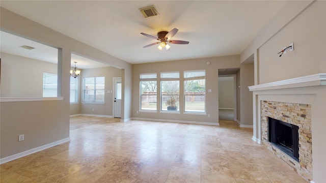 unfurnished living room with visible vents, baseboards, a stone fireplace, and ceiling fan with notable chandelier