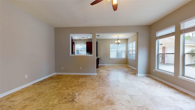 unfurnished room featuring baseboards and ceiling fan with notable chandelier