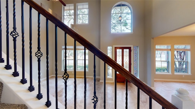 staircase with tile patterned floors, a high ceiling, and baseboards