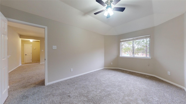 carpeted spare room with vaulted ceiling, a ceiling fan, and baseboards