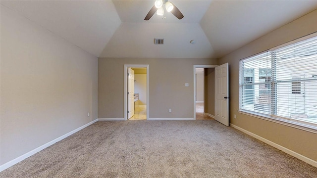 unfurnished bedroom featuring visible vents, baseboards, vaulted ceiling, light colored carpet, and connected bathroom